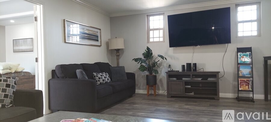 A living room with a grey couch and a flat screen TV mounted on the wall.