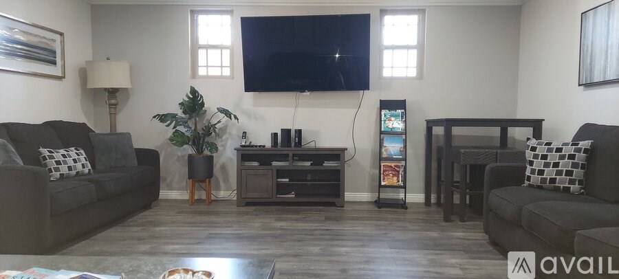 A living room with a grey couch and a television mounted on the wall.