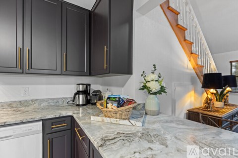 A kitchen with black cabinets and a marble countertop.