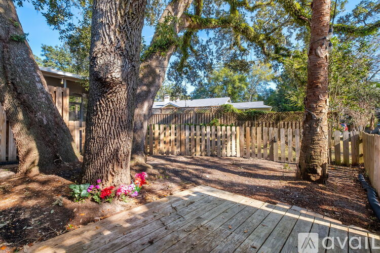 A wooden deck is surrounded by trees and a fence.