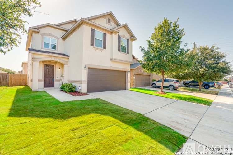 A two-story house with a garage is surrounded by a green lawn and a sidewalk.