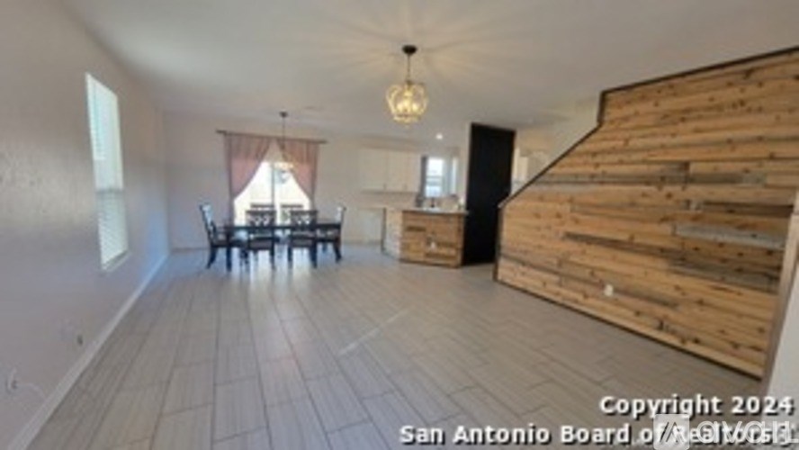 A room with wooden flooring and a dining table with chairs.