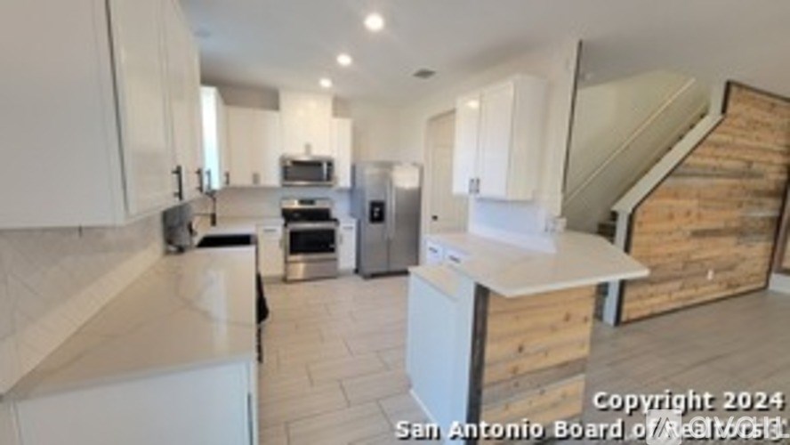 A kitchen with white cabinets and a wooden staircase.