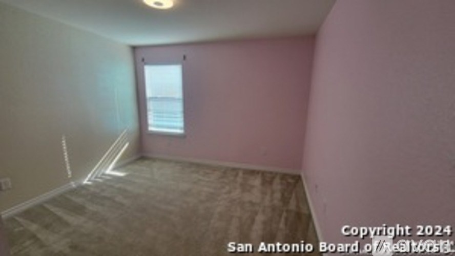 A room with pink walls and a window overlooking the water.