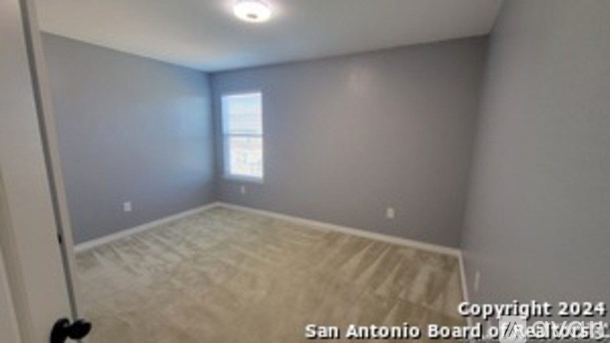 A room with a window and a light on the ceiling.
