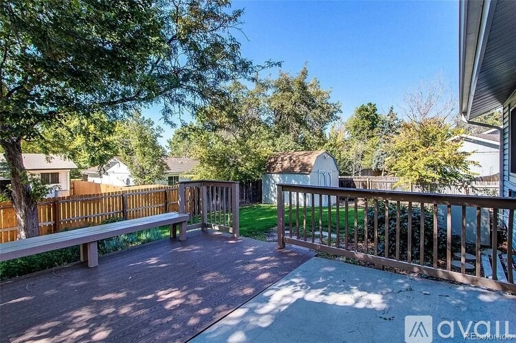A sunny day in a backyard with a wooden bench and a fence.