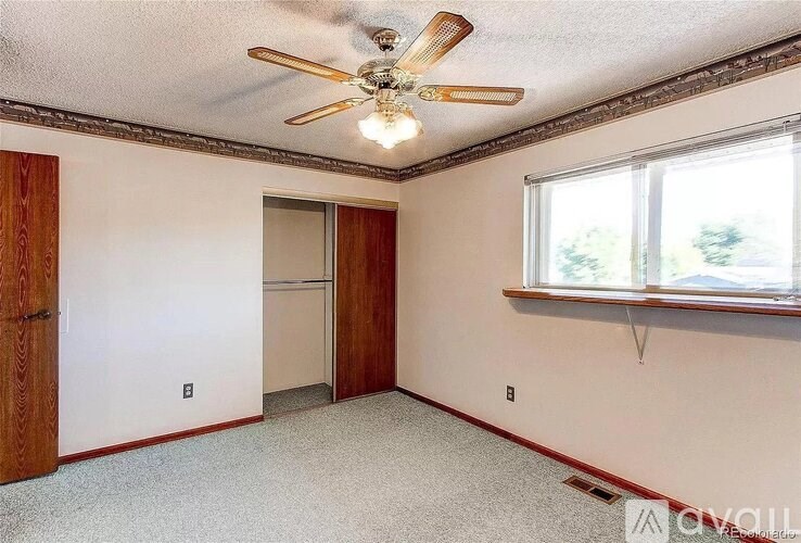 A room with a ceiling fan and a window.