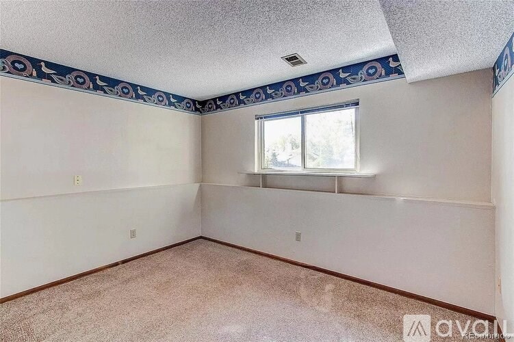 A room with a window and a blue and white border on the ceiling.