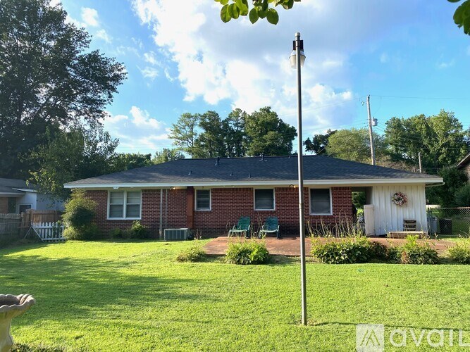 A house with a red brick exterior and a white door is surrounded by a green lawn.
