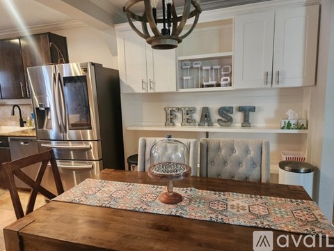 A kitchen with a table in the middle and a sign that says "FEAST" on the wall.