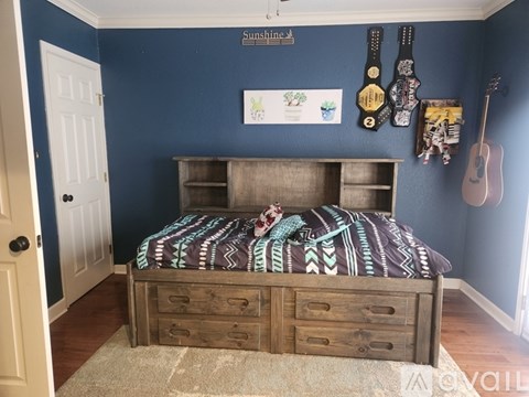 A bedroom with a bed, dresser, and guitars on the wall.