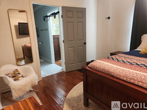 A bedroom with a bed, chair, and a mirror.