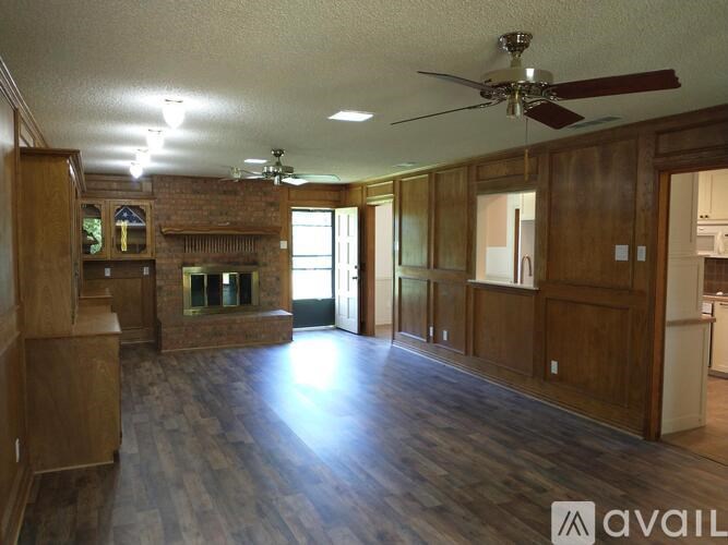 A living room with wood floors and a brick fireplace.
