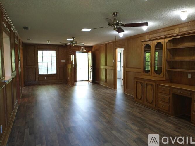 A spacious room with wooden floors and furniture.
