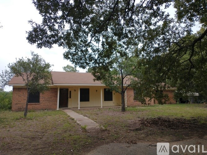 A house with a porch and a tree in front of it.