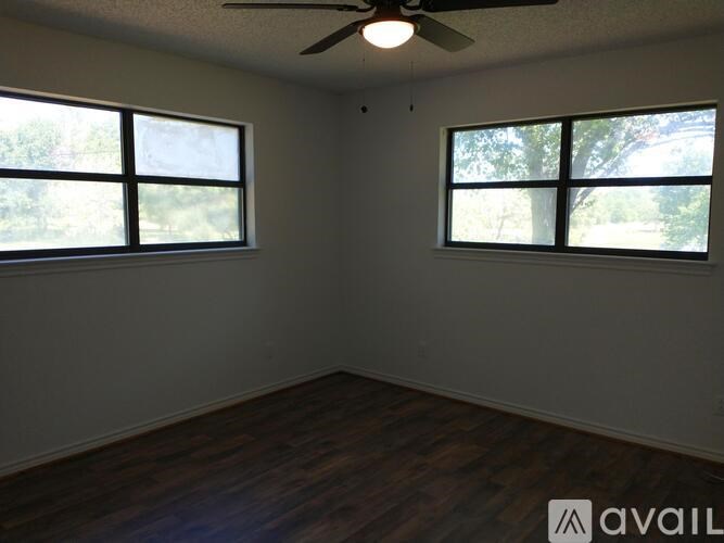 A room with a ceiling fan and two windows.