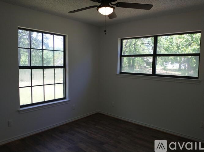 A room with a ceiling fan and two windows.