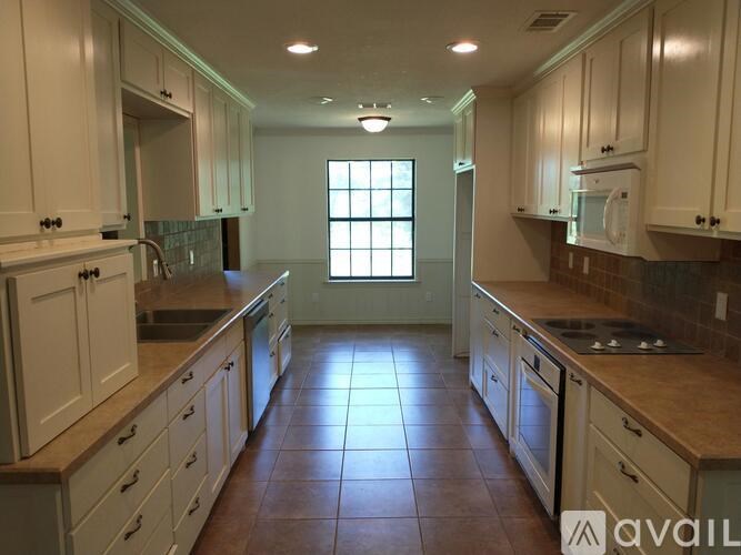 A kitchen with white cabinets and brown tile flooring.
