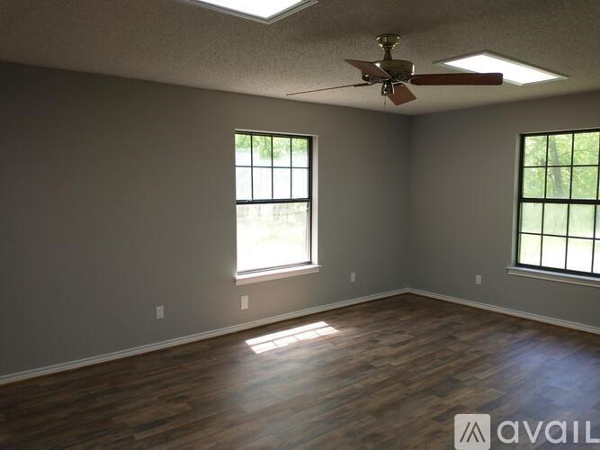 A room with a ceiling fan and two windows.
