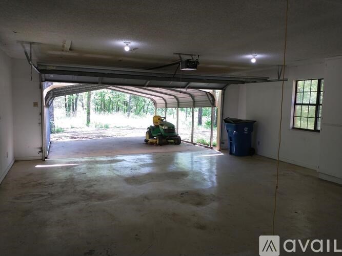 A large empty garage with a green lawn mower inside.