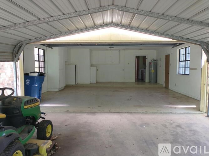 A green lawn mower is in a large, empty garage.