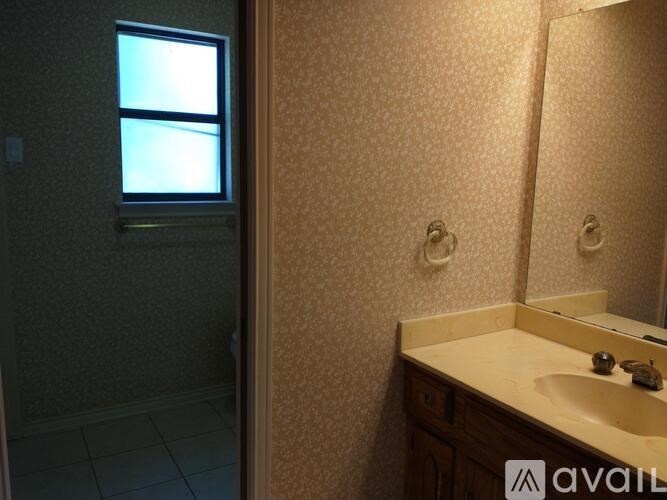 A bathroom with a sink, mirror, and a window.