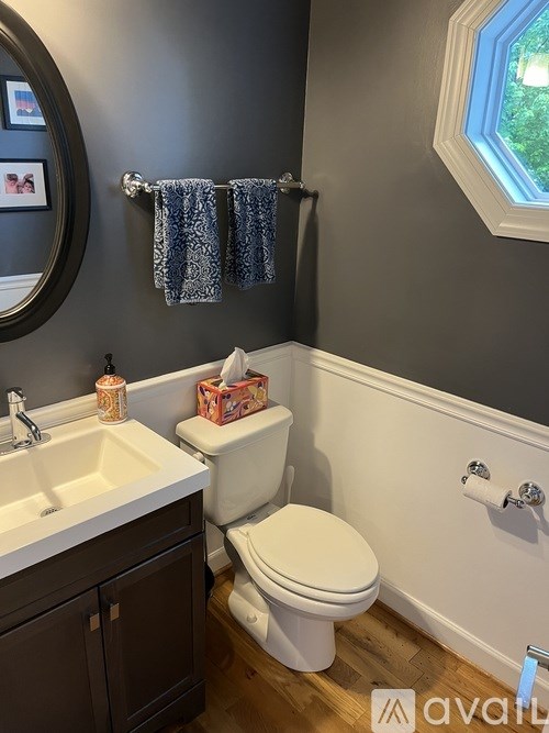 A bathroom with a toilet, sink, and a window.