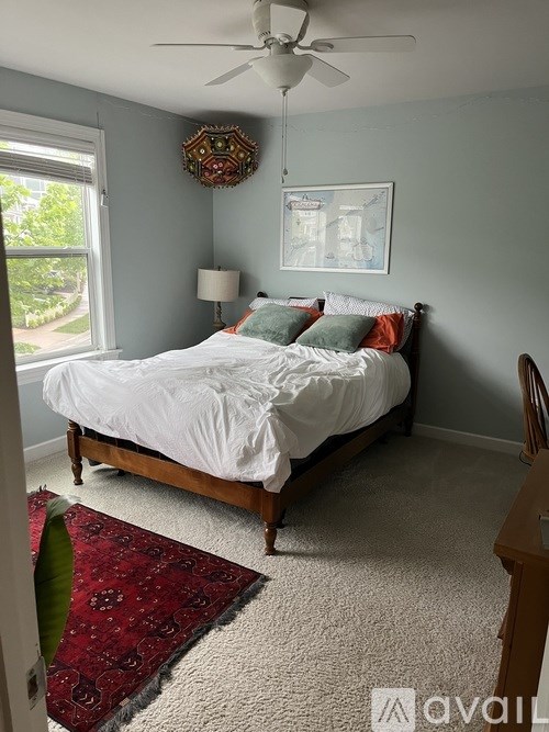 A bedroom with a bed, a ceiling fan, and a window.
