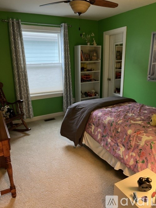 A bedroom with a bed, dresser, and window.