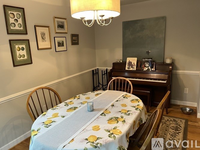 A dining room with a table set for two and a piano.