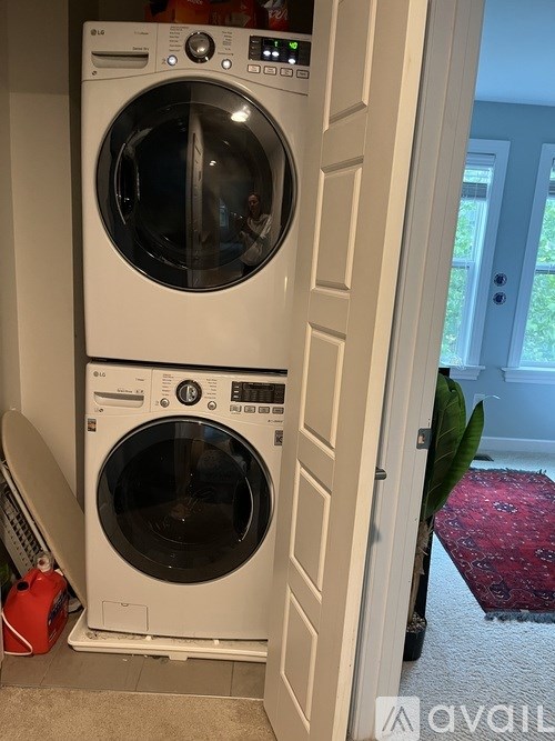 A white front loading washing machine with a red bag next to it.