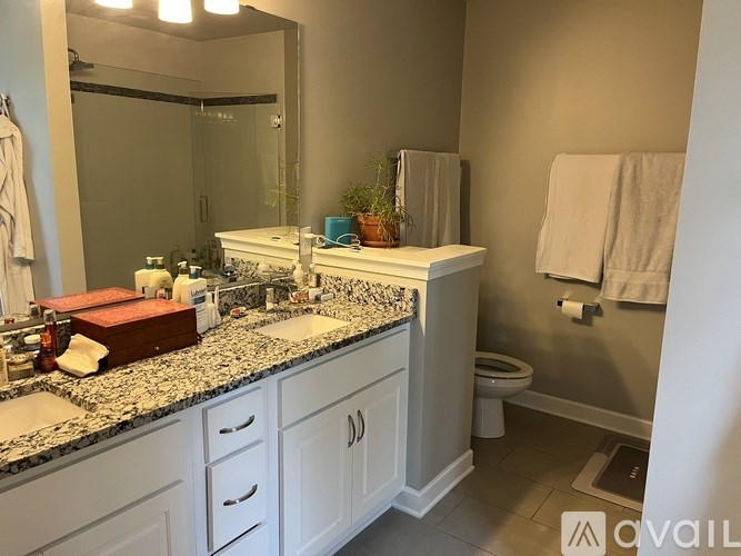 A bathroom with a marble countertop and white cabinets.