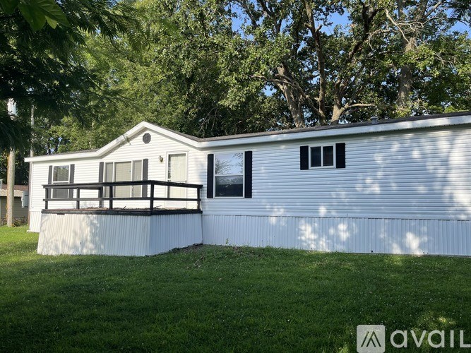 A mobile home with a porch and a tree in the background.