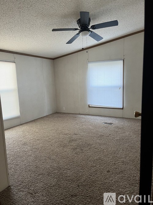 A room with a ceiling fan and carpeted floor.