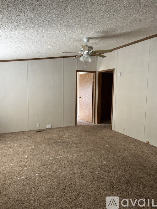A room with a ceiling fan and a door in the middle.