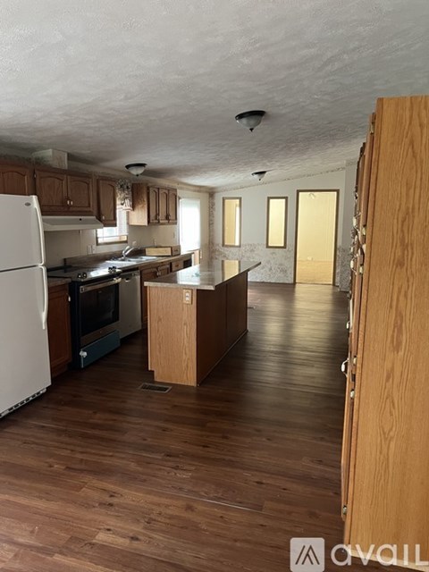 A kitchen with wooden floors and a white refrigerator.