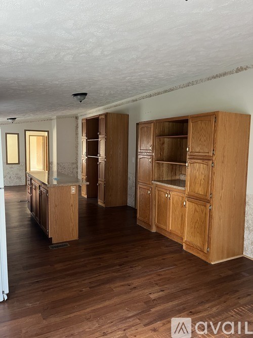 A room with wooden floors and furniture, including a wooden cabinet with glass doors.