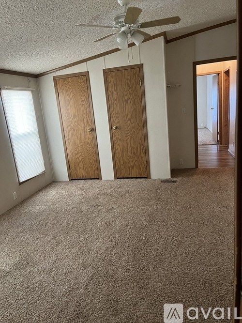 A room with a carpeted floor and a ceiling fan.