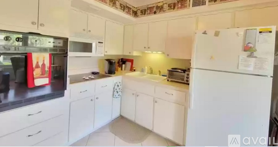 A kitchen with white cabinets and appliances, including a refrigerator, microwave, and oven.