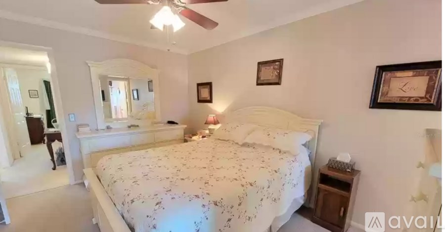 A bedroom with a large bed and a ceiling fan.