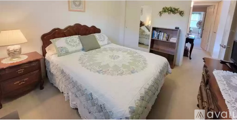 A bedroom with a large bed and a lamp on a side table.