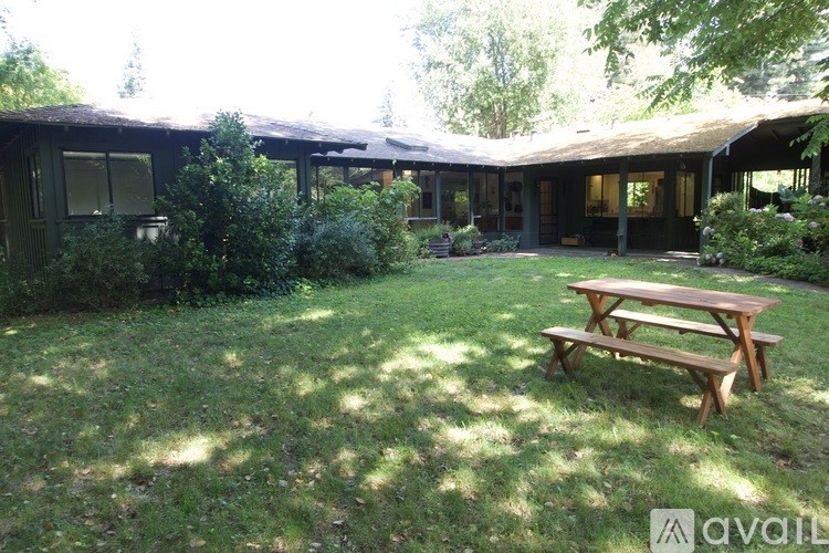 A wooden picnic table is in the middle of a grassy yard.