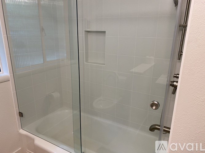 A glass shower door with a white tile wall behind it.