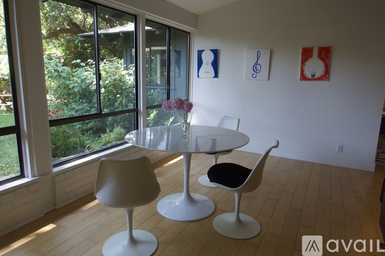 A white dining table with two chairs in front of a window.