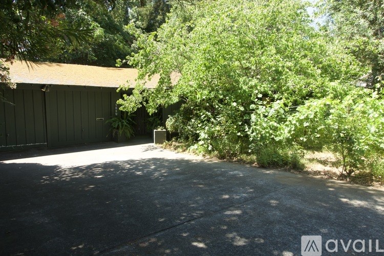 A parking lot with a building and trees in the background.