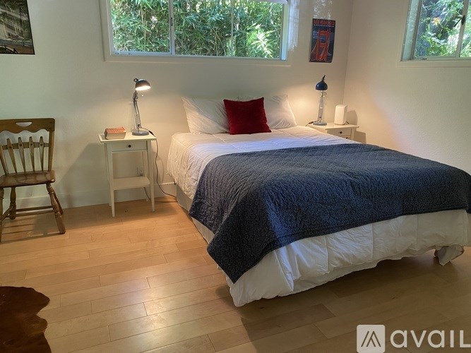 A bedroom with a bed, a chair, and two lamps.