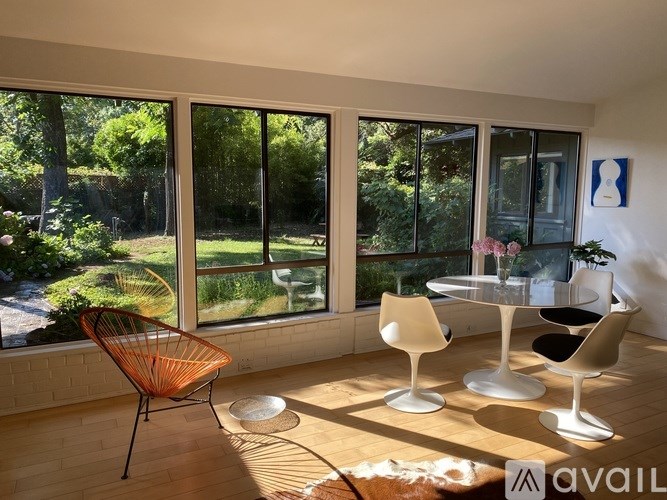 A room with a table and chairs and a view of a garden outside.