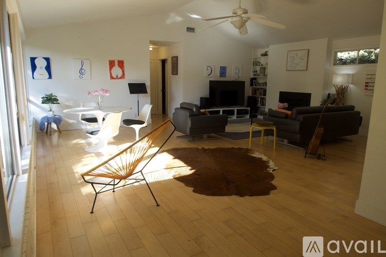 A living room with a brown cowhide rug and a white ceiling fan.