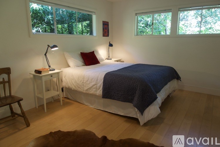 A bedroom with a bed, a chair, and two lamps.