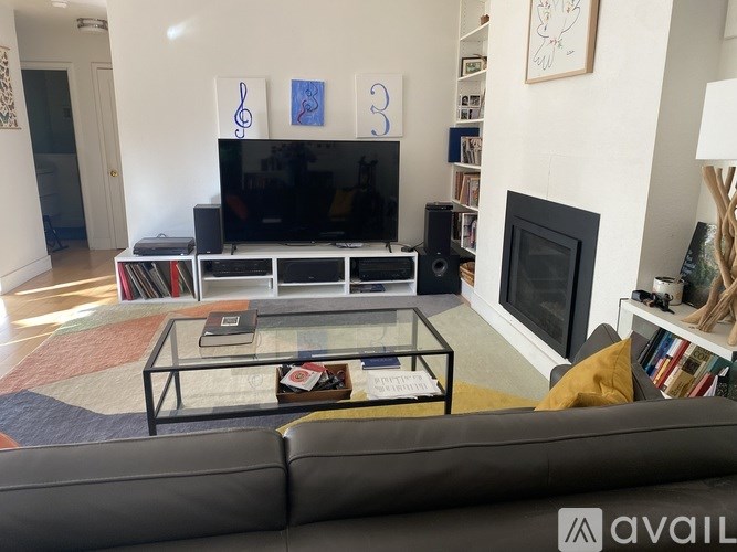 A living room with a grey couch and a glass coffee table.